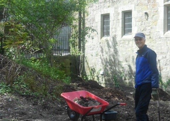 Volunteer standing with wheelbarrow outside cathedral