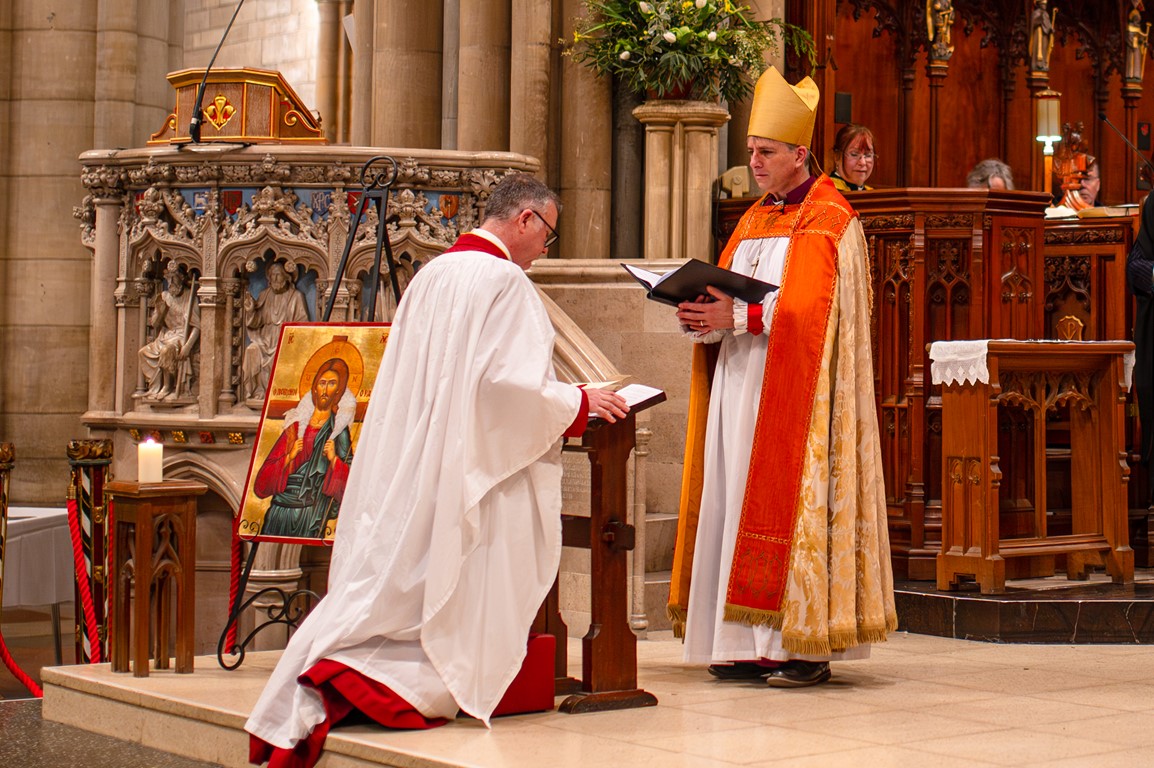 Dean Simon kneeling in front of the Bishop of St Germans for the official Installation 