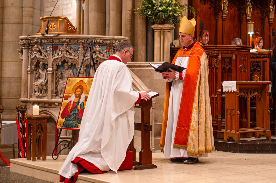 Dean Simon kneeling in front of the Bishop of St Germans for the official Installation