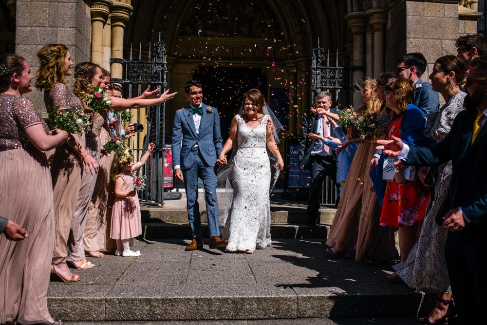 Bride and groom leaving the cathedral as guests throw confetti over the newlyweds.