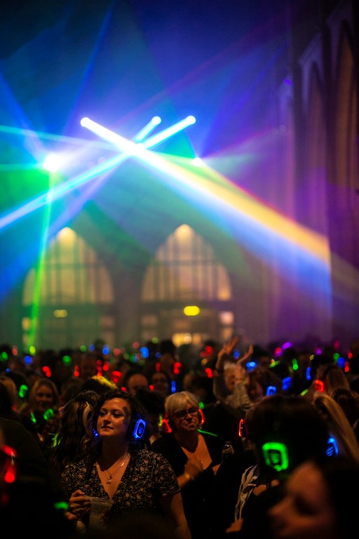 Crowds inside Truro Cathedral at the silent disco dancing beneath lasers