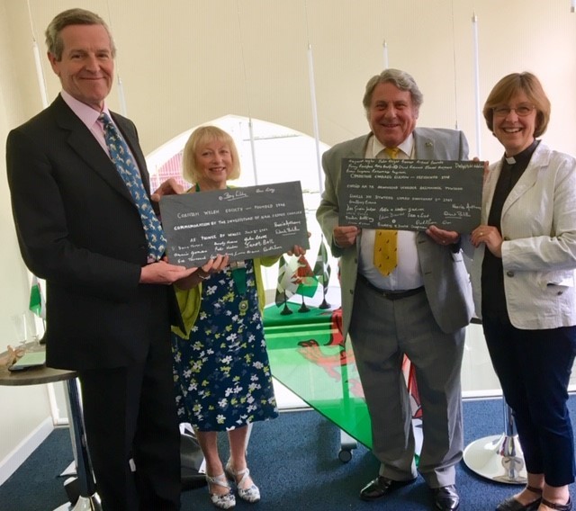 Members of the Cornish Welsh Society standing with Canon Lynda Barley holding the roof slates they have signed