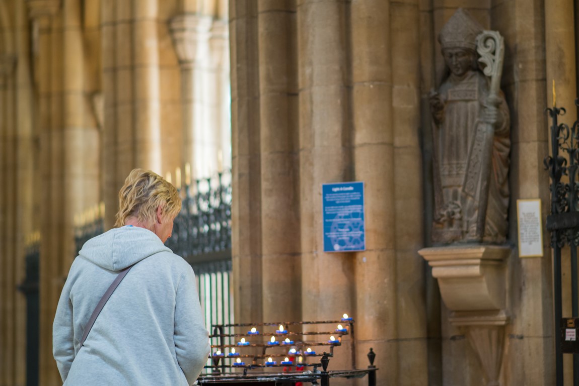 Person by pricket stand with lit candles in Truro Cathedral