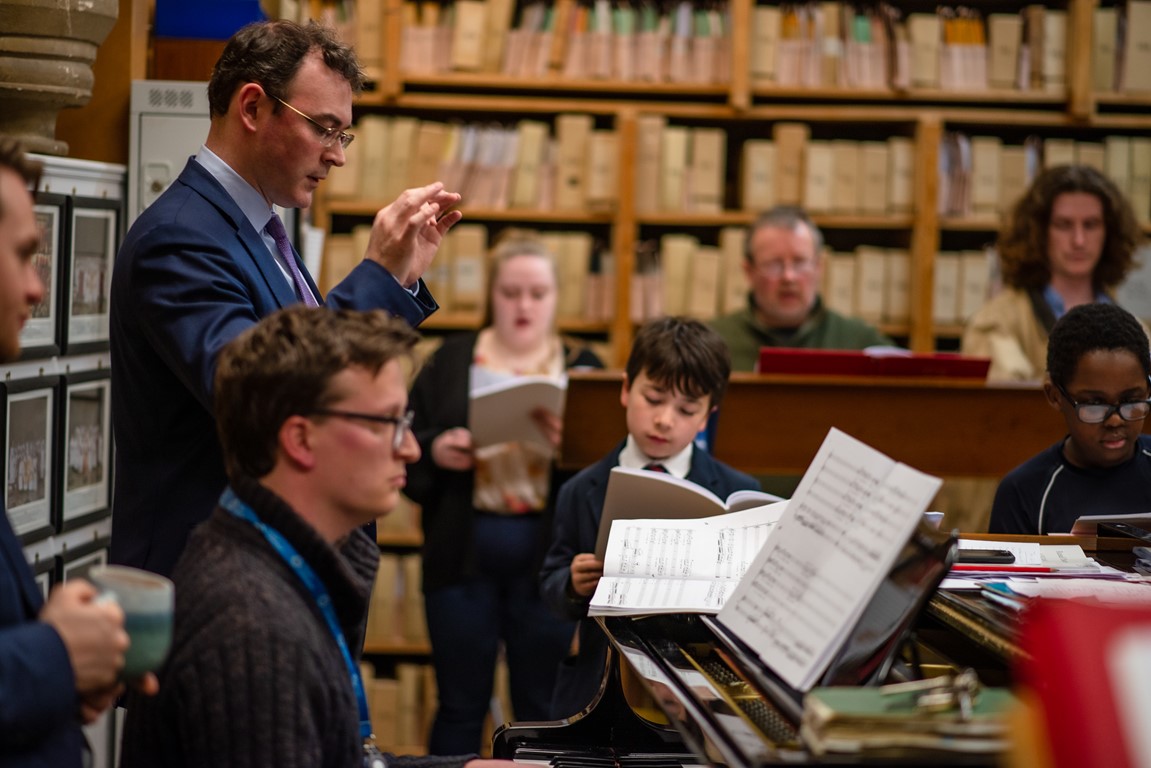 Christopher Gray director of music at Truro Cathedral conducting choristers in practice in the cathedral crypt 