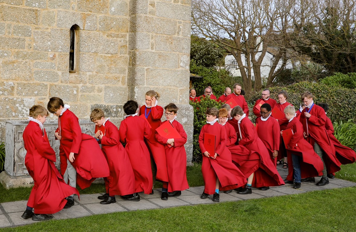 Truro Cathedral Choir in red cassocks caught in the wind before concert on Isle of Scilly